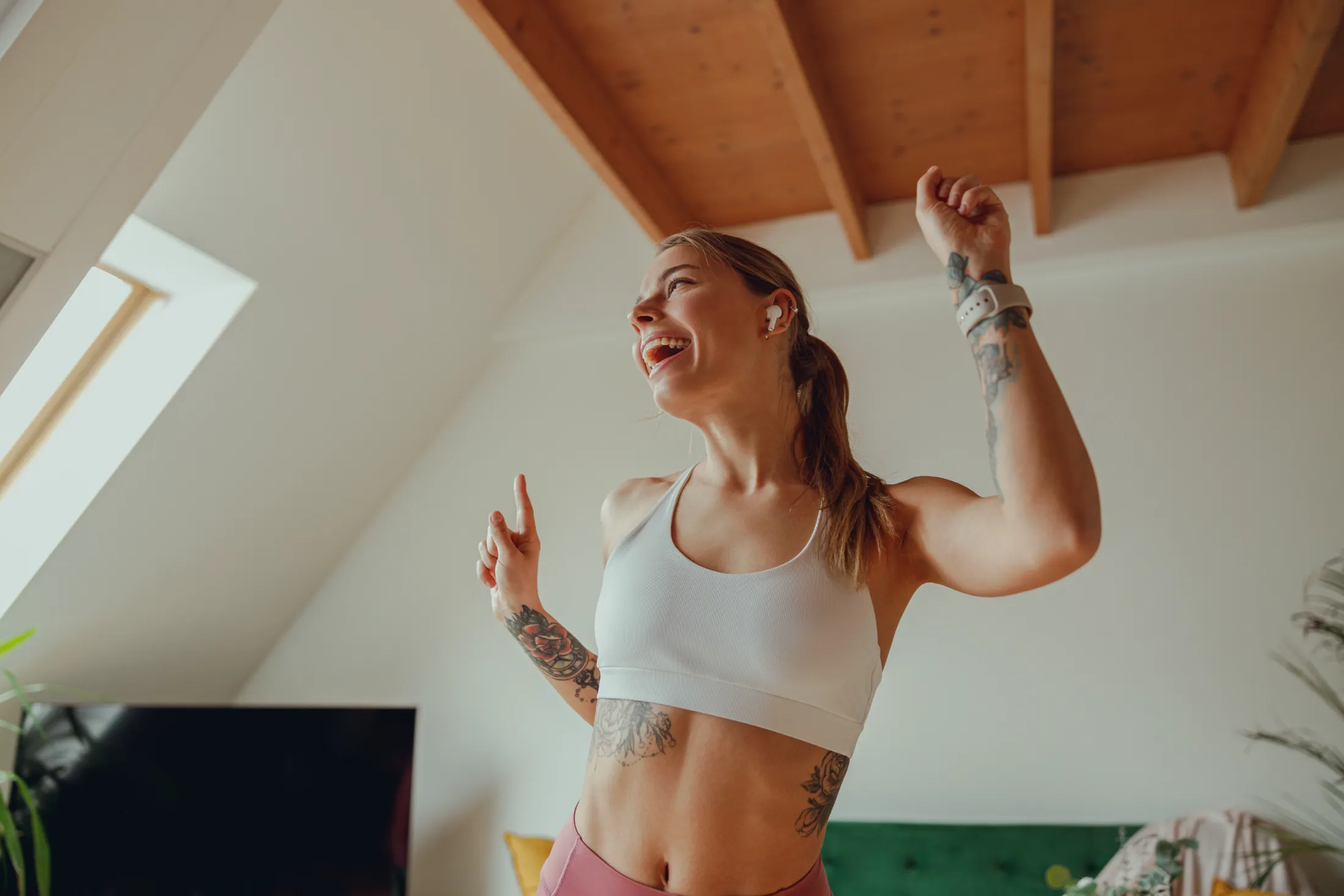 a woman dances in a living room raising her arms utc