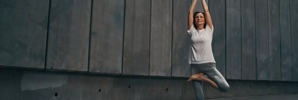 calm elderly slim female practicing yoga outdoors utc