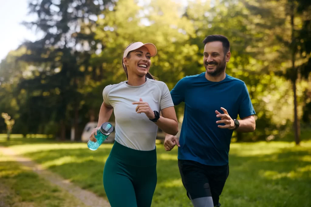 cheerful athletic couple jogging through the park utc
