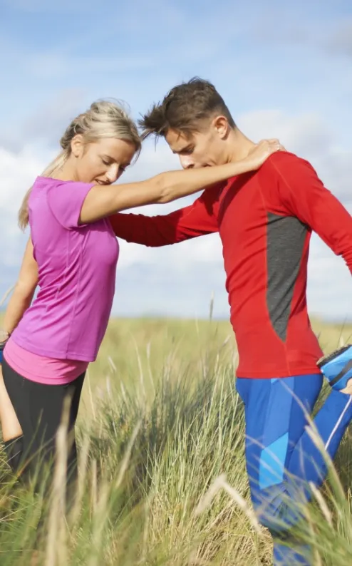 couple in tall grass on one leg doing stretching e utc