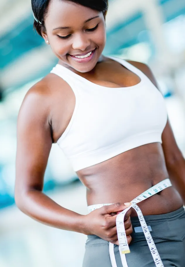 happy woman loosing weight at the gym and measurin utc